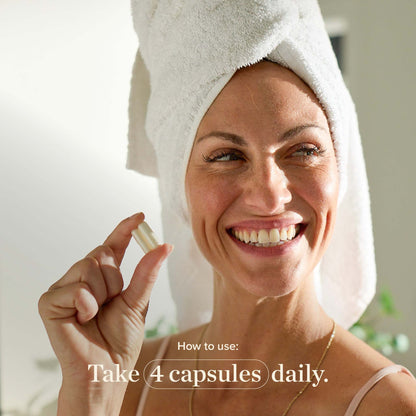 woman with towel on head holding Great Lakes Wellness Collagen Capsule smiling