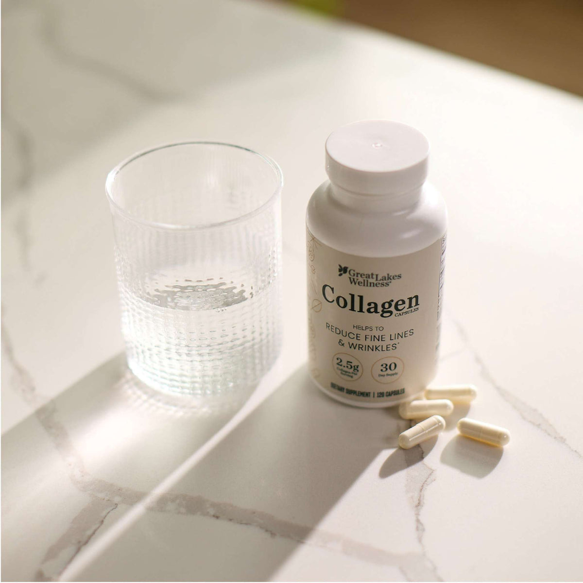 Great Lakes Wellness Collagen Capsules bottle with capsules and glass of water on marble surface for skin and hair health support
